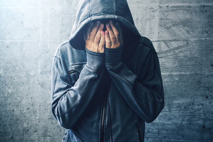 Depressão no delírio. Fonte da foto: Getty Images Comportamento de delírio depressivo. Homem, encapuzado, mãos no rosto.