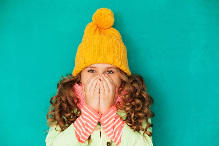 É importante distinguir a gripe de uma constipação ou resfriado. Fonte da foto: Getty Images A menina está vestida a rigor e cobre a cara com as mãos