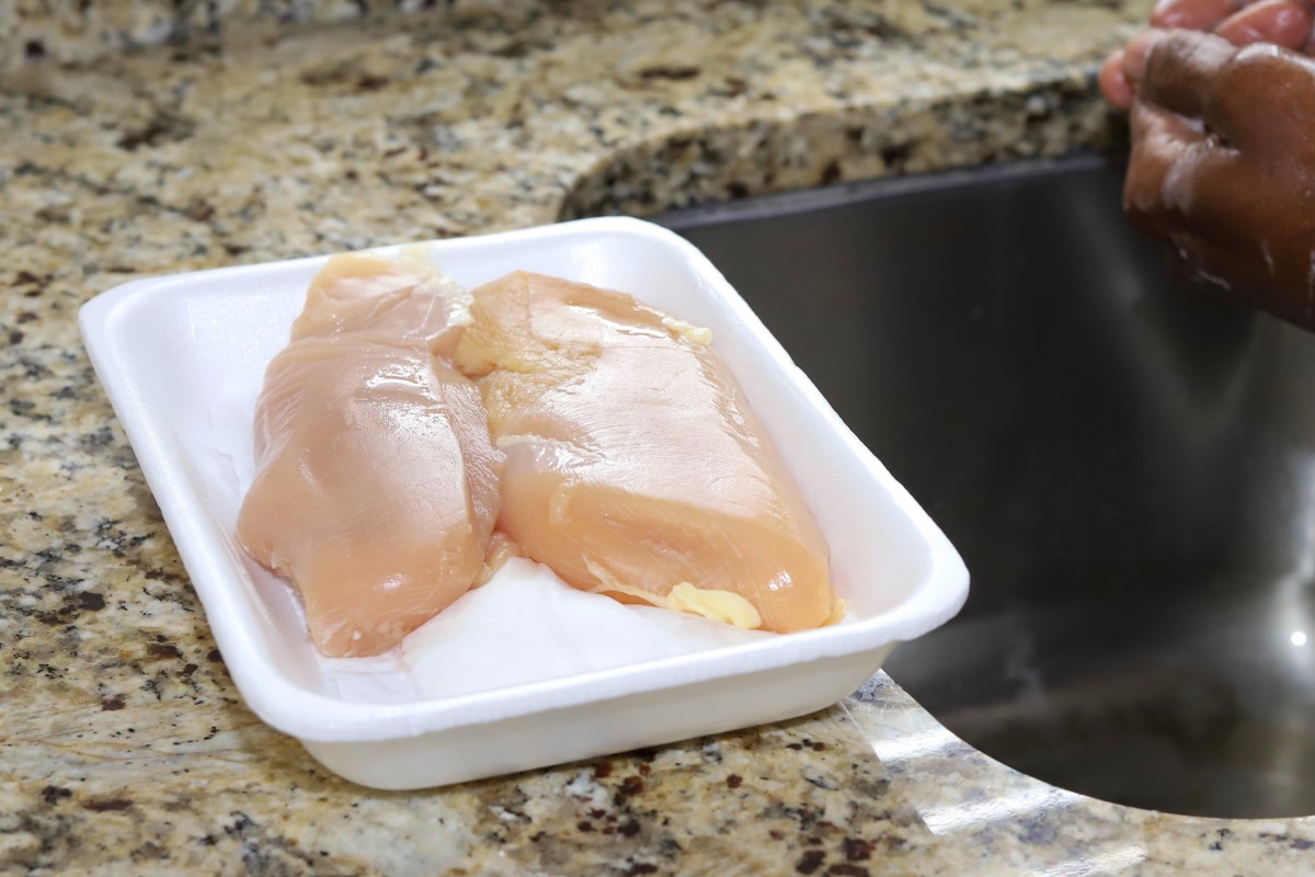 Atenção especial à higiene na preparação e transformação dos alimentos: Getty Images Frango num tabuleiro junto ao lava-loiça
