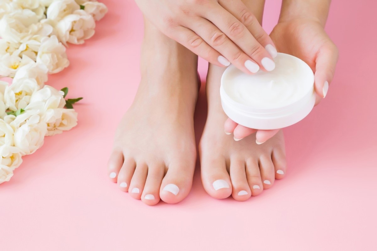 O creme para os pés também pode ajudar: Getty Images Aplicação de creme para os pés Uma mulher aplica creme nos pés com as mãos.
