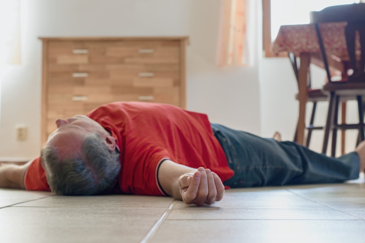 Um dos sintomas pode ser a perda de consciência. Fonte da fotografia: Getty Images Um homem inconsciente deitado no chão de uma casa