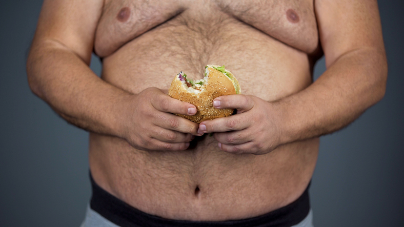 Dieta inadequada como causa. Fonte da foto: Getty Images Um homem, uma barriga grande e um hambúrguer