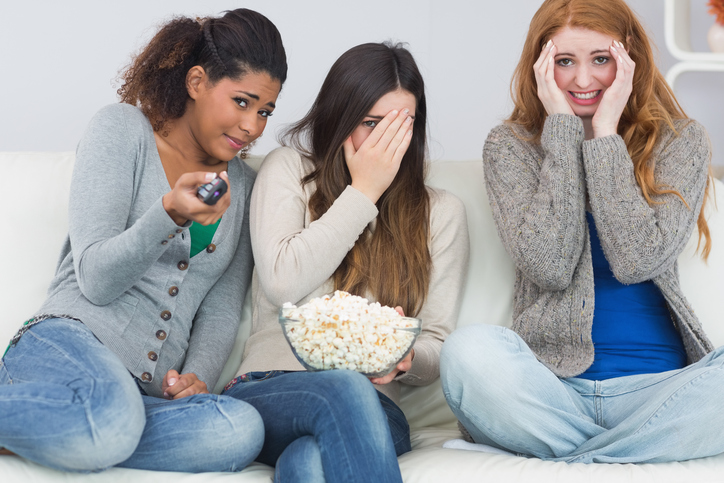 Pesadelos do filme. Fonte: Getty Images Três raparigas estão assustadas, vêem um filme de terror, pipocas numa tigela