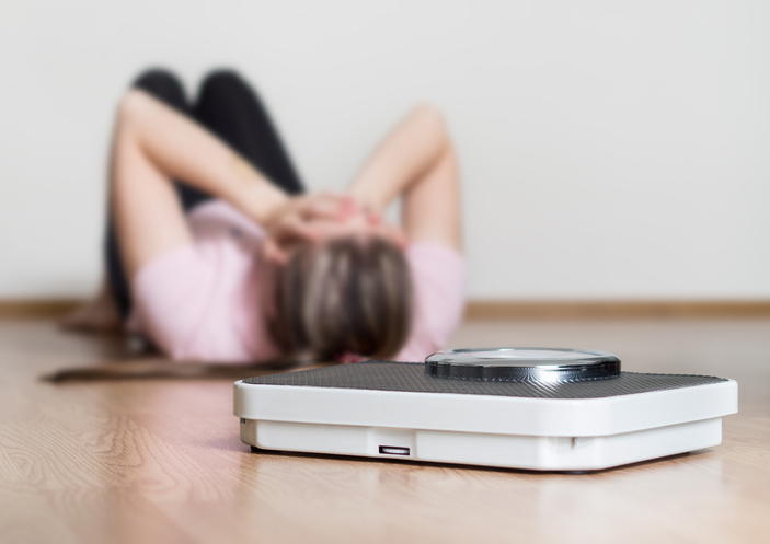Depressão, ansiedade, insatisfação com o peso. Fonte: Getty Images Bulimia - uma mulher deitada no chão, peso, peso corporal, ansiedade
