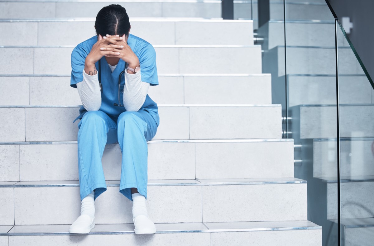 O esgotamento ocorre geralmente em determinadas profissões: Getty Images Uma enfermeira senta-se exausta nas escadas e sofre de síndrome de burnout
