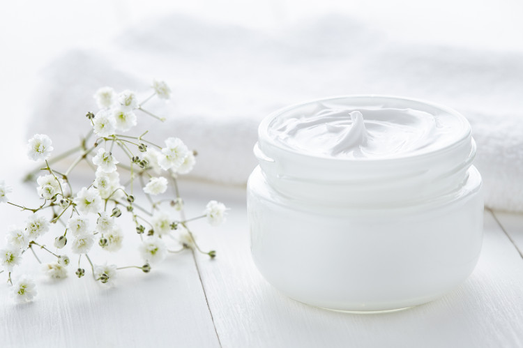 Hidratantes à base de óleo Fonte: Getty Images um frasco de creme branco no passeio, ao lado de uma toalha branca e de flores brancas