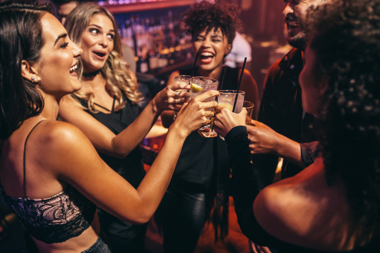 Os jovens, a sociedade e as bebidas acloholic. Fonte Getty Images um grupo de jovens a rir num estabelecimento de bebidas