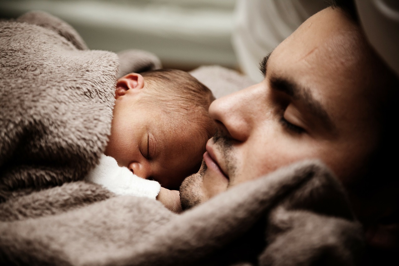 O sono das crianças e dos adultos difere significativamente Foto: Getty Images o bebé dorme ao lado do pai debaixo de um cobertor castanho