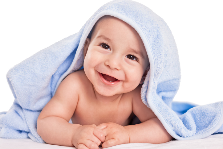 É importante deixar a pele do seu bebé respirar livremente de vez em quando. Fonte: Thinkstock um bebé risonho de barriga para baixo, coberto com uma toalha