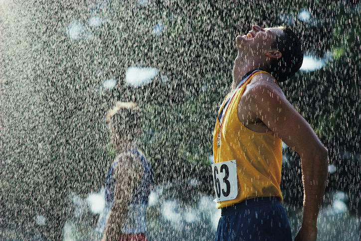 Até a prática de desporto em todas as condições meteorológicas faz parte do processo de endurecimento. Fonte: Thinkstock Um atleta depois de passar a meta. Está a chover. Tem a cabeça virada para cima contra as gotas que caem. Tem os olhos fechados e uma medalha ao pescoço. Veste uma camisola de alças amarela com o número 63 e calções azuis.