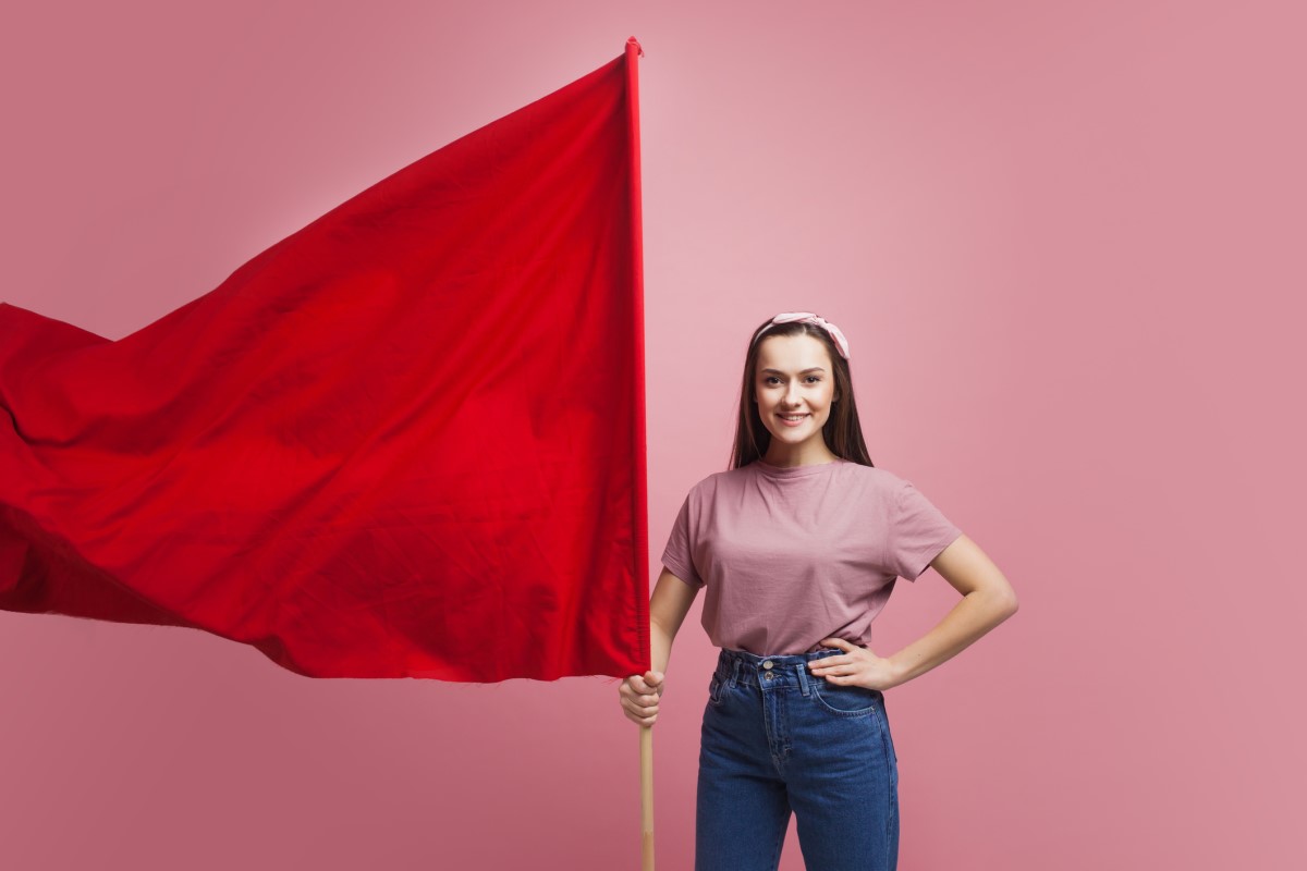 Uma mulher segura uma grande bandeira vermelha como aviso.