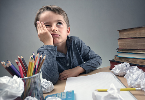 Perturbação de défice de atenção. Foto: Getty Images um estudante sentado à secretária, a pensar em algo, com um caderno, papel e lápis em cima da secretária