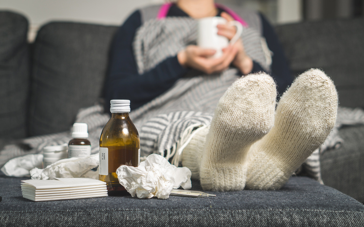 Rinite, inflamação, inchaço, faringite - tudo isto pode apanhá-lo de surpresa onde quer que esteja. Fonte: Thinkstock uma mulher doente está deitada na cama com meias quentes e comprimidos e xaropes ao seu lado