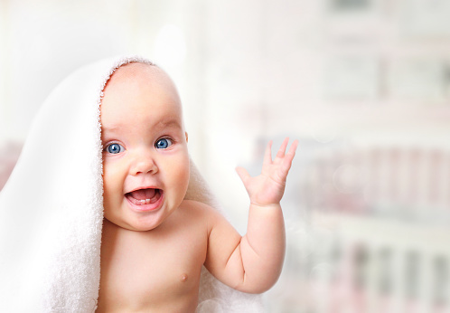 Um sono de qualidade garante um bebé feliz. Foto: Getty Images Bebé a rir debaixo do cobertor