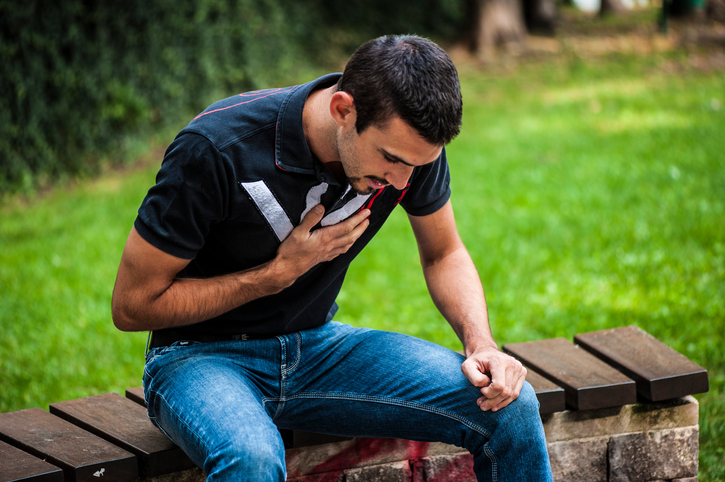 Dor no peito, sensação de falta de ar Fonte da foto: Getty Images Jovem sentado num banco de jardim, segurando o peito, dor no peito, dificuldade em respirar