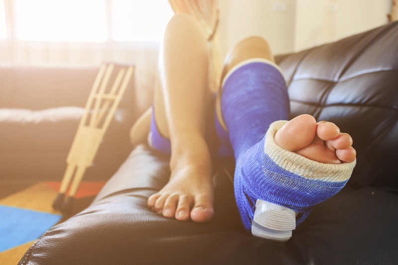 O repouso e a utilização de analgésicos têm um lugar indispensável no tratamento. Fonte: Getty Images. Um homem na cama com uma cinta e muletas.