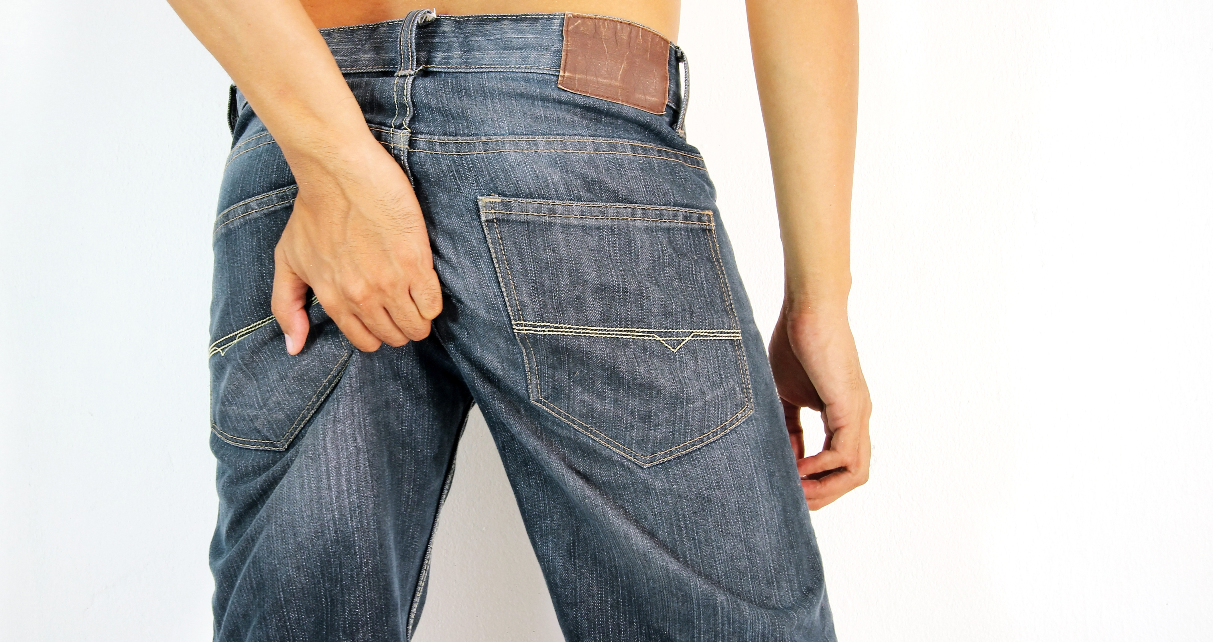 A via mais comum de transmissão da enterite viral é a transmissão fecal-oral (ânus-boca). Foto: Thinkstock homem de calças de ganga a coçar o rabo