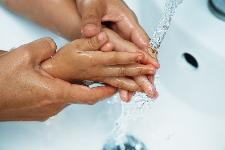 Os hábitos de higiene desde a primeira infância são essenciais. Fonte: Thinkstock mãos da mãe sobre o lava-loiça lavar as mãos do bebé em água corrente