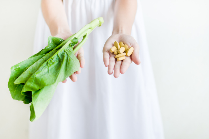 Não só na gravidez, prefira uma folha de alface fresca a uma quantidade excessiva de suplementos nutricionais. Fonte: Thinkstock Mãos a segurar comprimidos e folhas de salada