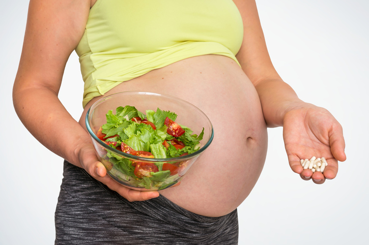 Vivemos numa época em que há abundância de alimentos e não falta deles, mas o problema é a composição da dieta. Fonte da foto: Getty Images Mulher grávida com salada e comprimidos