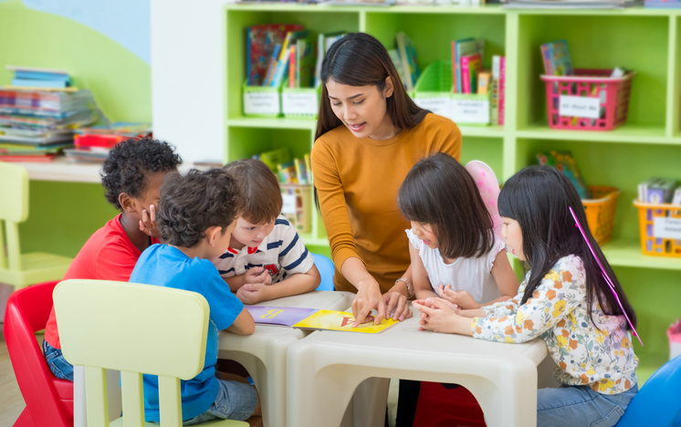 O filtro matinal garante a saúde e previne o reaparecimento de doenças nas crianças. Fonte Getty Images Uma educadora de infância lê um livro para as crianças
