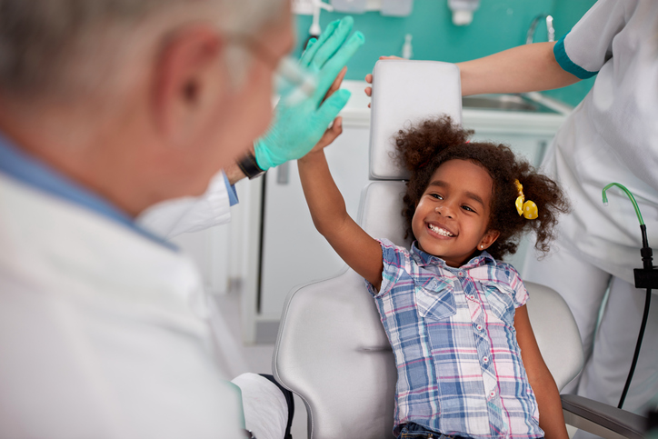 Uma prevenção adequada evitará experiências desagradáveis para o seu filho na cadeira do dentista. Fonte: Thinkstock a rapariga risonha na cadeira do dentista com o dentista.