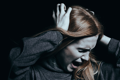 Agressão. Fonte: Getty Images a mulher está a segurar o cabelo e a gritar, é agressiva