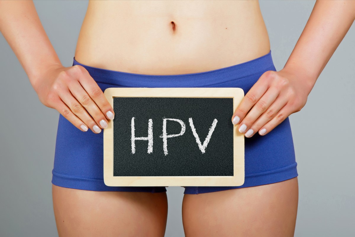 Mulher a segurar um cartaz que diz HPV