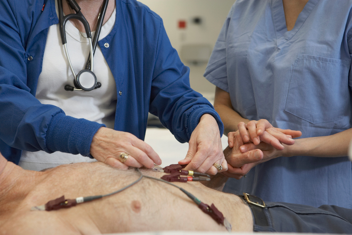 Exame de ECG do homem, eléctrodos no peito, dois médicos a examiná-lo