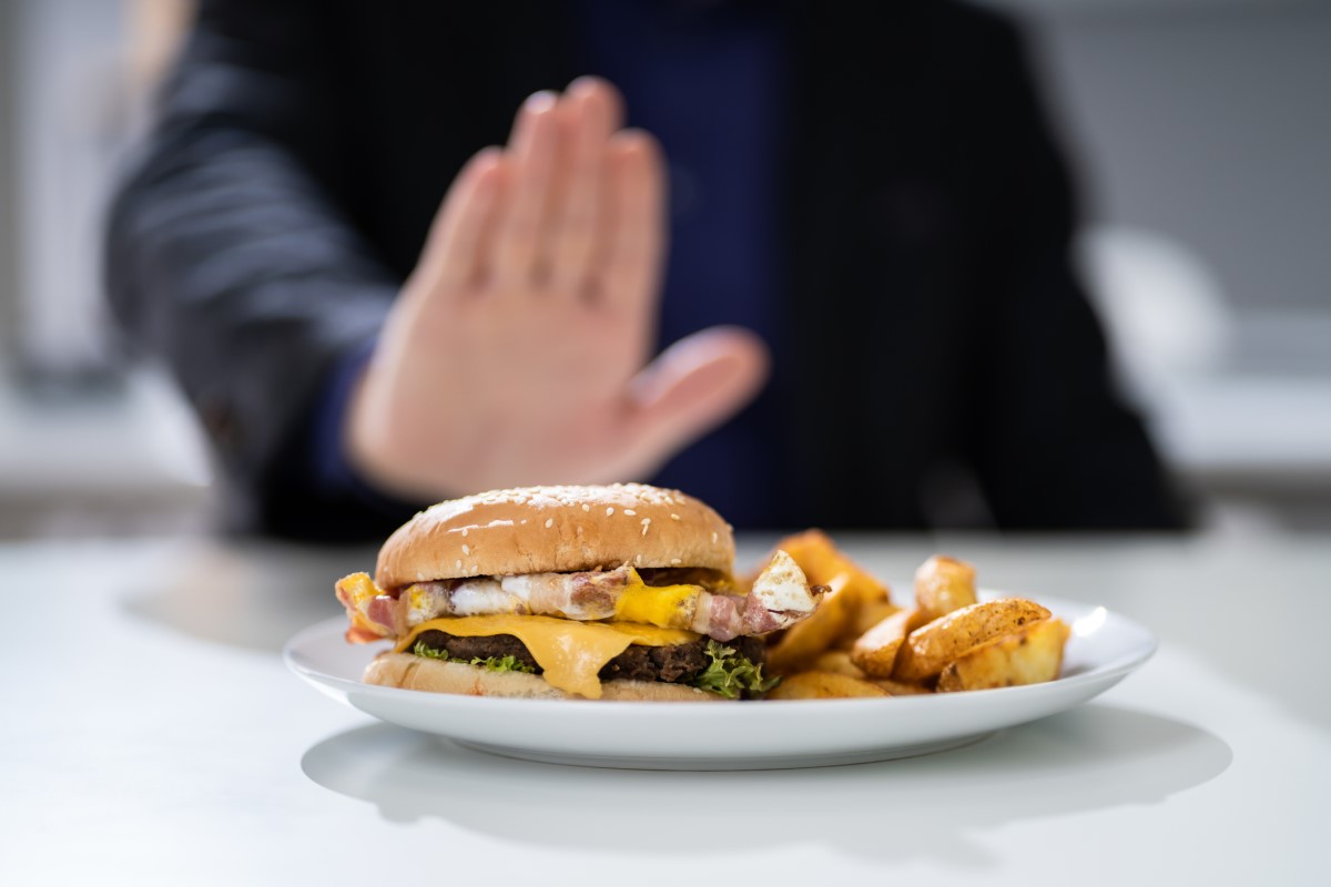 Alimentos inadequados e erro alimentar como causa comum de azia. Fonte da foto: Getty Images Alimentos inadequados como causa de azia - um hambúrguer num prato que um homem recusa