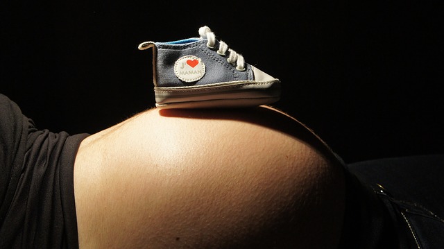 uma mulher grávida está deitada com um sapato em cima da barriga
