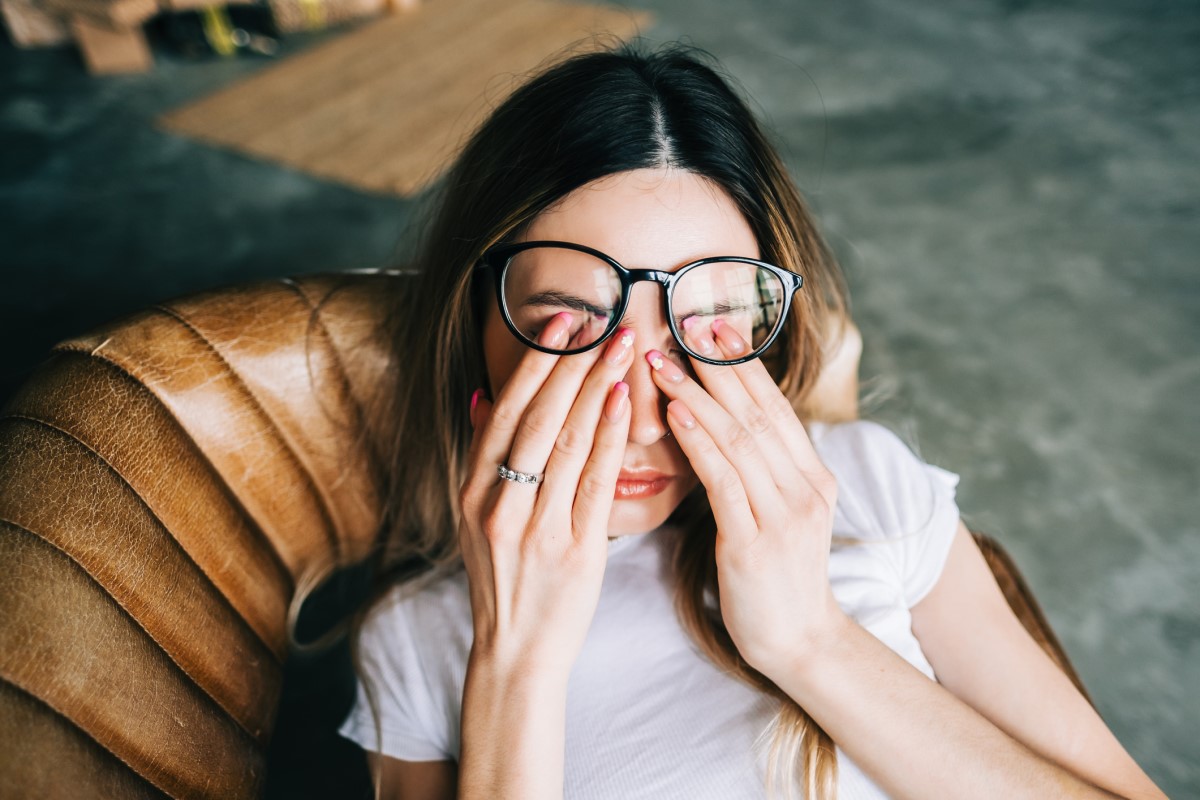 Uma mulher cansada deita-se no sofá, com os olhos fechados.