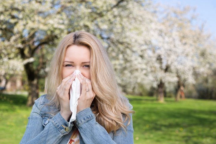 A febre dos fenos é uma forma de alergia que, para além de corrimento nasal, pode provocar espirros: Getty Images A mulher tem febre dos fenos, espirra, está ao ar livre, relva e flores de árvores