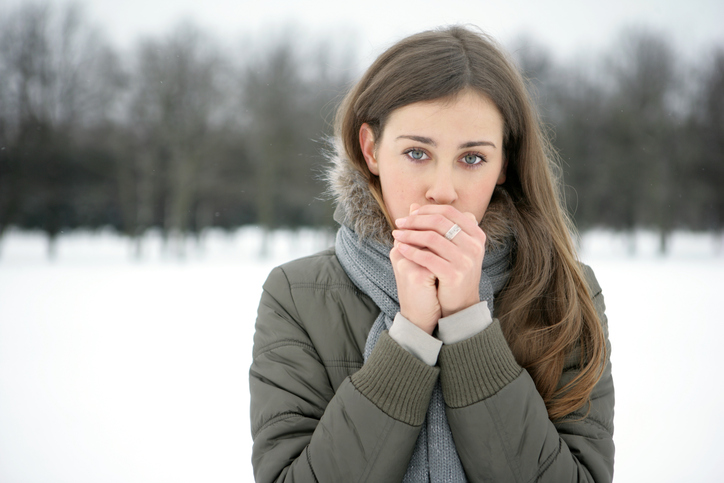 Uma mulher aquece os seus membros frios com a sua respiração, está a nevar lá fora, frio, frio