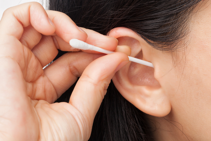 A higiene adequada é importante, mas tenha cuidado para não danificar o tímpano. Fonte da foto: Thinkstock photos uma mulher limpa o ouvido com um cotonete
